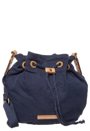 Granatowa bawełniana torba typu bucket z zapięciem na ściągacz, akcentami z brązowej skóry, regulowanym paskiem na ramię oraz małą prostokątną etykietą marki.