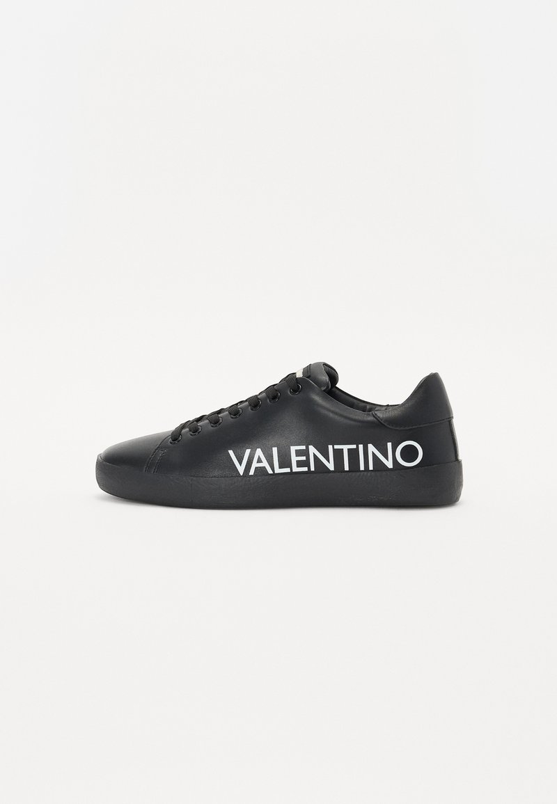 Baskets en cuir noir avec une pointe arrondie, semelle plate noire et logo "VALENTINO" blanc proéminent sur le côté. Design lacé avec six œillets.