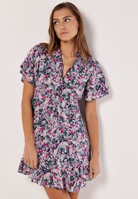 Blumenkleid mit kurzen Rüschärmeln, einem V-Ausschnitt und einem ausgestellten Saum. Hauptfarben sind Dunkelblau, Pink und weiße Blumenmuster.