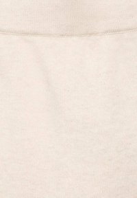 Tissu couleur crème avec une finition douce et texturée. Présente une taille lisse et un motif de tricot homogène. Pas de logos ou de motifs visibles.