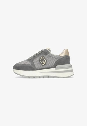 Sneaker grigia e beige con dettagli in rete e camoscio, suola bianca spessa ed emblema metallico sul lato.