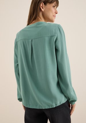 Blusa verde menta con una vestibilità morbida, caratterizzata da righe verticali, maniche lunghe e scollo tondo con dettaglio a piega sul retro.