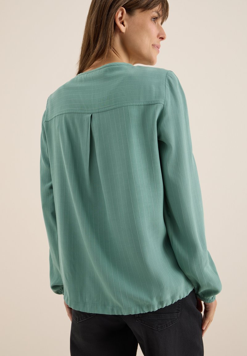 Blusa verde menta con una vestibilità morbida, caratterizzata da righe verticali, maniche lunghe e scollo tondo con dettaglio a piega sul retro.