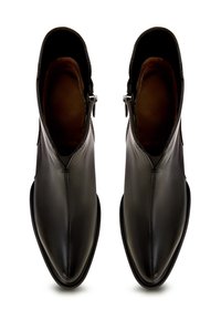 Bottines en cuir noir avec une texture lisse, bout pointu et fermeture éclair sur le côté. L'intérieur est doublé d'un matériau marron.