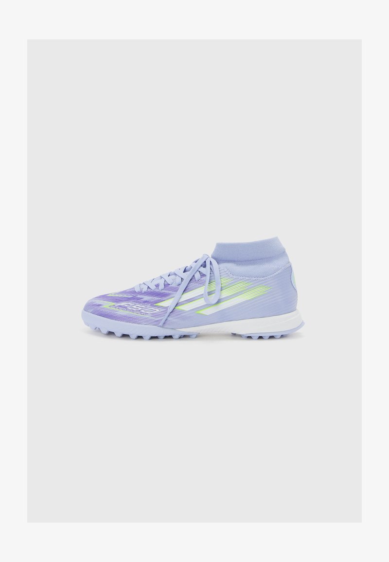Zapatilla deportiva de color púrpura claro con un cuello tipo calcetín, parte superior texturizada, acentos en verde neón y suela blanca con múltiples pequeños tacos.