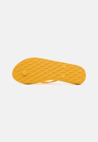 Gul gummiflip-flop sula med en texturerad design med diamantmönster och två runda indragningar.
