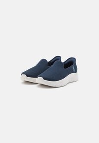 Scarpe slip-on in rete navy con suola bianca, caratterizzate da una tomaia testurizzata e un branding minimale sul tallone. Design leggero e traspirante.