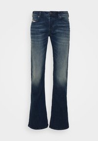 Mörkblå bootcut jeans med urblekta områden på låren, knappstängning och femficksdesign visade på en vit bakgrund.