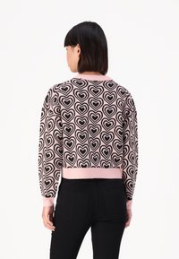 Maglione accorciato con motivo a cuori rosa e neri, polsini e orlo a costine, e scollatura rotonda. Materiale in maglia morbida.