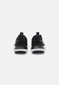 Baskets en tricot noir avec une finition texturée et des accents blancs. Dotées d'une semelle rembourrée et de languettes au talon pour un enfiler facile.