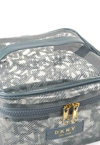 Bolsa de cosméticos de colores gris y blanco con un diseño claro, acabado suave, cierre de doble cremallera y una etiqueta de marca DKNY en un parche texturizado.