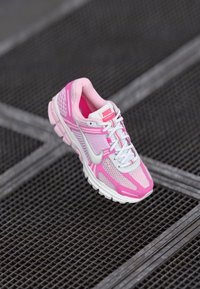 Nike trkaći model cipela s gornjim dijelom od mrežaste tkanine u ružičastoj i bijeloj boji, podstavljenim đonom i reflektirajućim detaljima. Lagani dizajn koji osigurava udobnost i potporu.