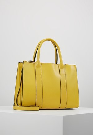 Gul læderhåndtaske med dobbelte håndtag og en aftagelig skulderrem, vist på en hvid piedestal mod en ensfarvet baggrund.