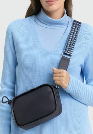 Schwarze, rechteckige Umhängetasche aus glattem Leder. Sie verfügt über einen gemusterten, verstellbaren Gurt und einen abgerundeten Reißverschlusszipper.