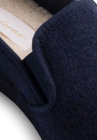 Navyblauwe slipper van vilt met een zachte voering. Voorzien van een ronde vorm en een elastische zijzijde voor gemakkelijke toegang.