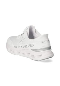 Chaussure de sport blanche Skechers Glide-Step avec semelle épaisse et coussinée, dessus en mesh, design à lacets et marquage gris sur le côté et le talon.