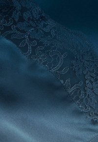 Satinmaterial i mörkblått med ett blommönstrat spetsöverdrag, som har intrikata mönster och en slät textur tillsammans med genomskinliga sektioner.