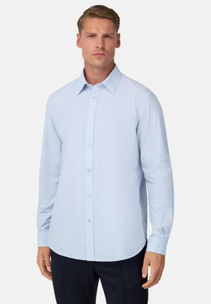 Camisa de vestir a rayas azul claro con mangas largas, cuello abotonado y dobladillo curvado, que presenta una textura suave y un brillo sutil.