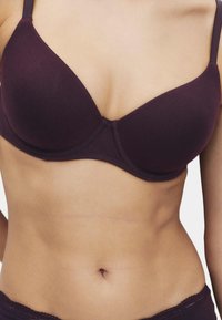 Mørkelilla, polstret bh med justerbare stropper, der har en glat stoftekstur og et sømløst design. Klassisk undertrådssupport.