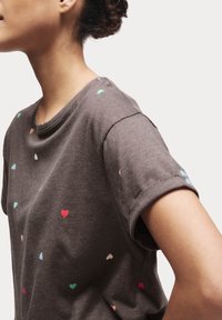 Grå kortærmet t-shirt med små multicolore hjerte mønstre. Blødt stof med en afslappet pasform og rund halsudskæring.