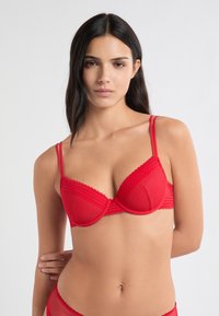 Roter Bügel-BH mit Spitzenbesatz, verstellbaren Doppelträgern und glattem Stoff. Geformte Körbchen mit runder Form und weicher Textur.