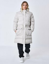 Lys grå dunsjakke med hætte, indsnævret talje, to frontlommer og quiltet tekstur, parret med sorte cargo bukser og hvide sneakers.