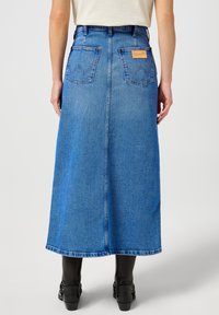 Denim maksiseelik, helesinine värv, kõrge vöökoht, seljataskud ja nahklogo, sirge lõige ja kergelt laienev äär.
