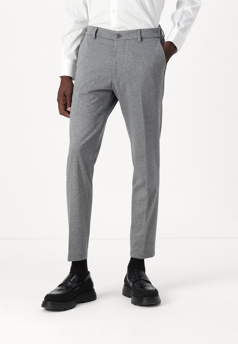 Grå skreddersydde bukser laget av teksturert stoff, med slim fit, beltehemper og skrålegg, kombinert med svarte loafers.