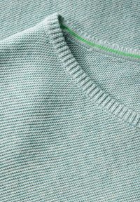 Maglione in blu chiaro a maglia con colletto a coste e cuciture di accento verdi. La trama è liscia con cuciture uniformi in tutto il capo.