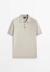 Polo beige clair à manches courtes avec col et trois boutons sur le devant, posé à plat sur un fond blanc.