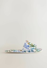 Plokščia basutė su balta baze, puošta mėlynais, žaliais ir geltonais gėlių raštais, ir plačia audinio juosta per pėdą.