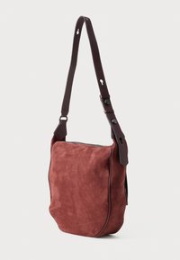 Borsa a spalla rossa in suede con finitura texture, dotata di una tracolla in pelle marrone e chiusura con zip sulla parte superiore. Design compatto e strutturato.