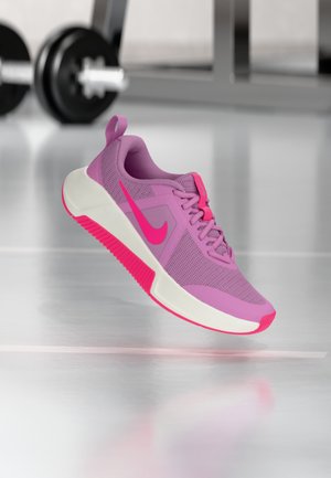 Zapatilla deportiva morada con parte superior de malla, detalles en rosa y entresuela blanca. Cuenta con suela exterior texturizada y prominente logo Nike Swoosh en rosa.