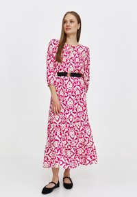 Różowa i kremowa sukienka w kwiatowy wzór z długimi rękawami, czarnym paskiem, falbaniastym dołem oraz szczegółem w kształcie dziurki w dekolcie. Nosi się z czarnymi balerinami.