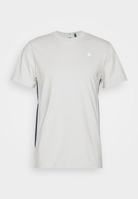 Jednoduché světle šedé tričko s krátkým rukávem a kulatým výstřihem, s malým bílým logem na levém prsu a tmavými bočními panely.