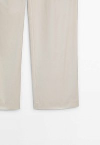 Beżowe spodnie wykonane z lekkiego materiału. Prosta nogawka o gładkiej fakturze, z bocznymi kieszeniami i bez widocznych ozdób.