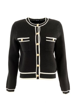 Cárdigan negro texturizado con ribete blanco, que presenta botones dorados y dos bolsillos en el pecho. El diseño incluye un escote redondo y mangas ajustadas.