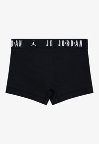 Black cotton boxer shorts featuring a wide elastic waistband with "JORDAN" printed in white lettering, and a minimalist design with smooth texture.