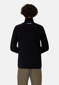 Pullover in pile nero con colletto alto, dotato di un logo sul retro e maniche lunghe. Texture liscia e vestibilità casual.