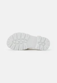 Semelle de sneakers blanche avec un motif de semelle profonde, en matériau en caoutchouc et surface texturée ; présente des sections surélevées pour une meilleure traction et stabilité.