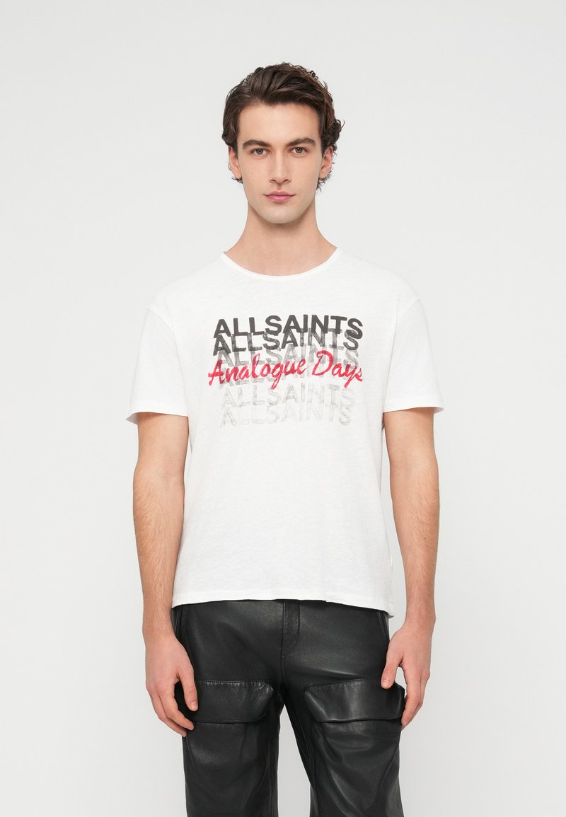 Λευκό βαμβακερό t-shirt με κείμενο "ALLSAINTS" σε μαύρο και κόκκινο, λαιμόκοψη crew, κοντά μανίκια και άνετη εφαρμογή. Κανονικό τελείωμα.
