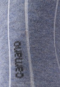 Knitted blue socks with a textured pattern, featuring light and dark blue stripes and a black logo on the side.