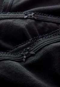 Zwart stoffen close-up met delicate kantafwerking en kleine satijnen strikjes. Zachte textuur met zichtbare stiksels. Eenvoudig en schoon ontwerp.