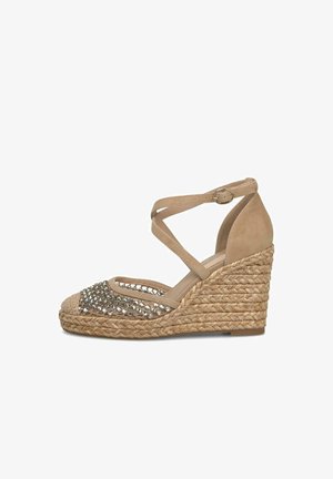 Sandalo con zeppa beige con piattaforma in corda intrecciata, cinturini alla caviglia incrociati e parte frontale decorata con borchie argento.