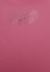 Camiseta de algodón rosa con un logotipo de Nike en patrón de puntos degradados en blanco y negro. Cuello redondo con textura suave.