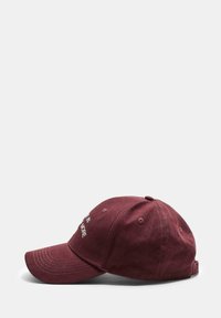 Cappellino da baseball in cotone bordeaux con visiera curva, testo ricamato sul davanti e fori di ventilazione sulla corona. Vista laterale.