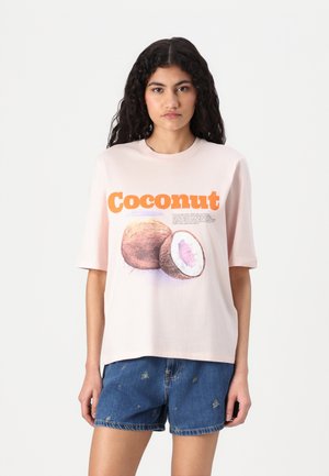 Lichtroze katoenen t-shirt met een afbeelding van een kokosnoot, voorzien van oranje tekst met de tekst "Kokosnoot" en gedetailleerde illustraties van de vrucht.