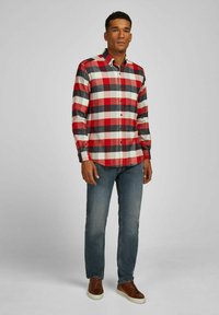 Rood en zwart geruite blouse met een kraag, lange mouwen en een rechte pasvorm, gecombineerd met een blauwe spijkerbroek en bruine schoenen.