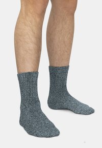Grau gestrickte Socken mit einem strukturierten Muster und einem gerippten Bündchen. Das Material wirkt weich und dick, bietet Wärme und Komfort.