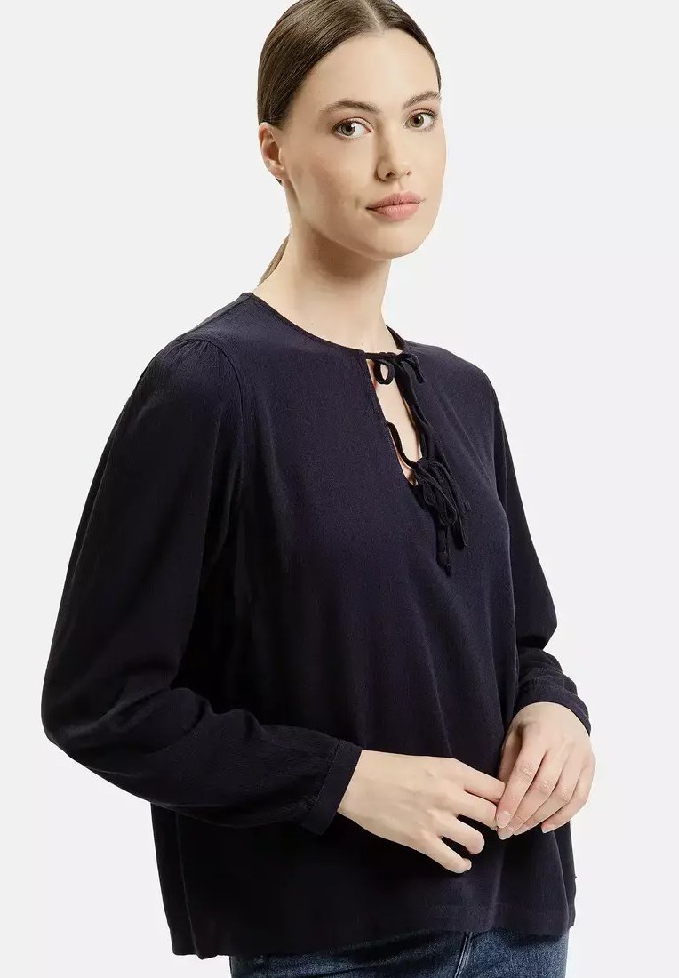 Ciemnoniebieska damska bluzka z długim rękawem, okrągłym dekoltem i detalem związania z przodu, uszyta z teksturowanej tkaniny. Prosty, luźny krój.
